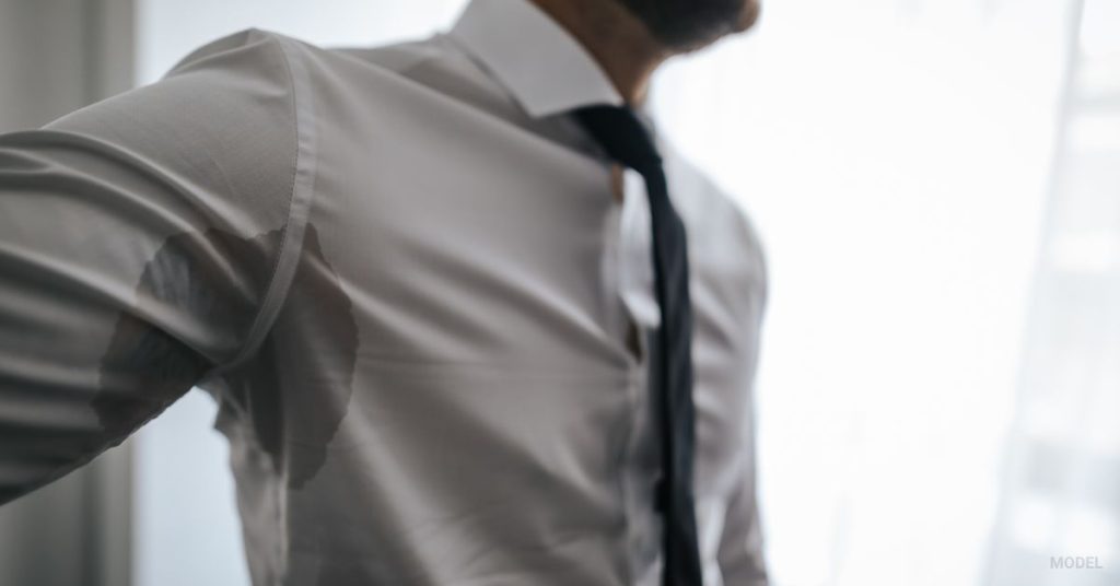 man in button up shirt at work sweating (MODEL)